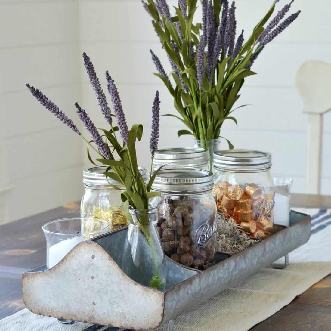 galvanized farmhouse style tray as table centerpiece holding candy, flowers and candle