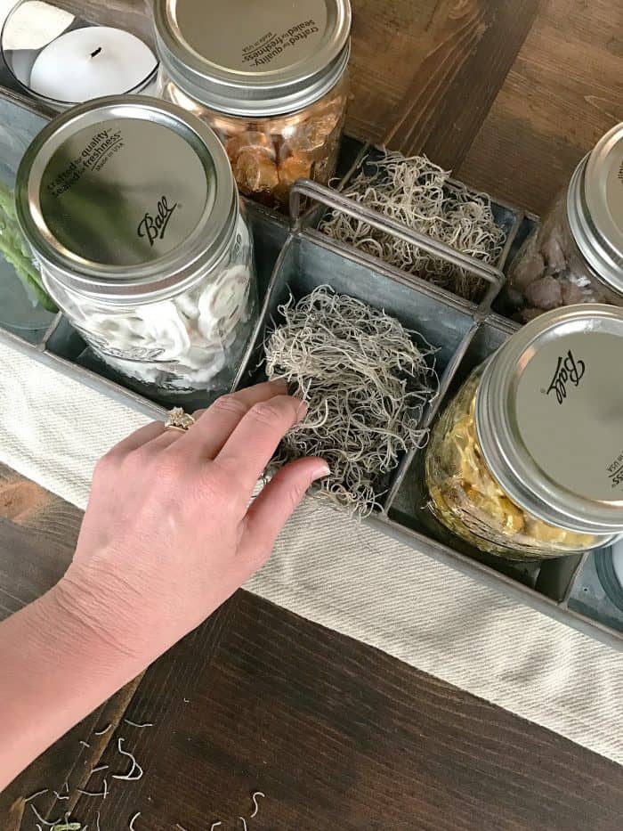 Galvanized farmhouse style tray filled with ball jars of candy and Spanish moss