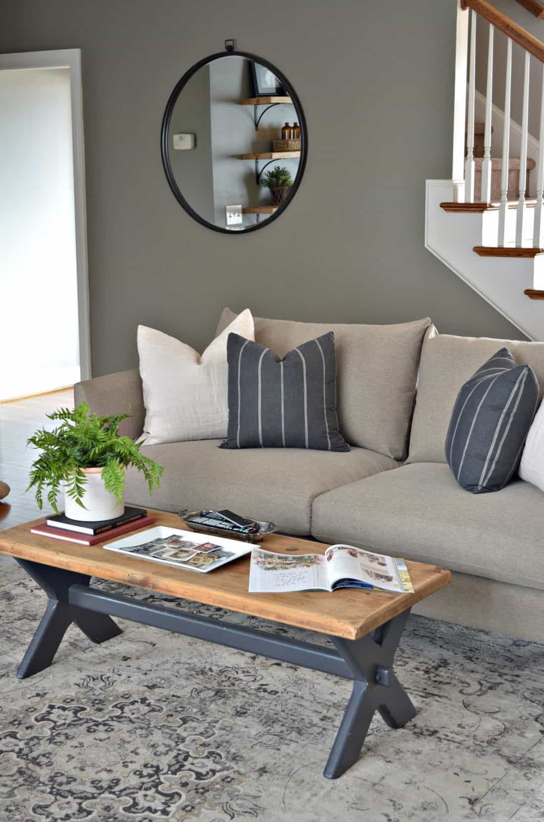 Living room sofa, vintage wood coffee table and round mirror on wall