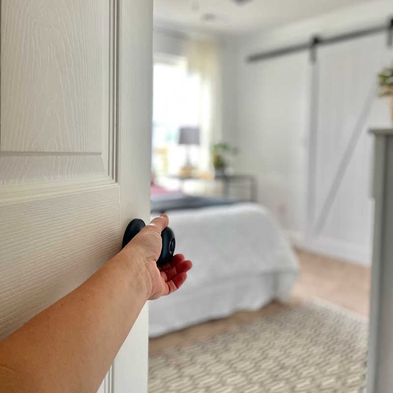 Open door to white, simple, uncluttered bedroom