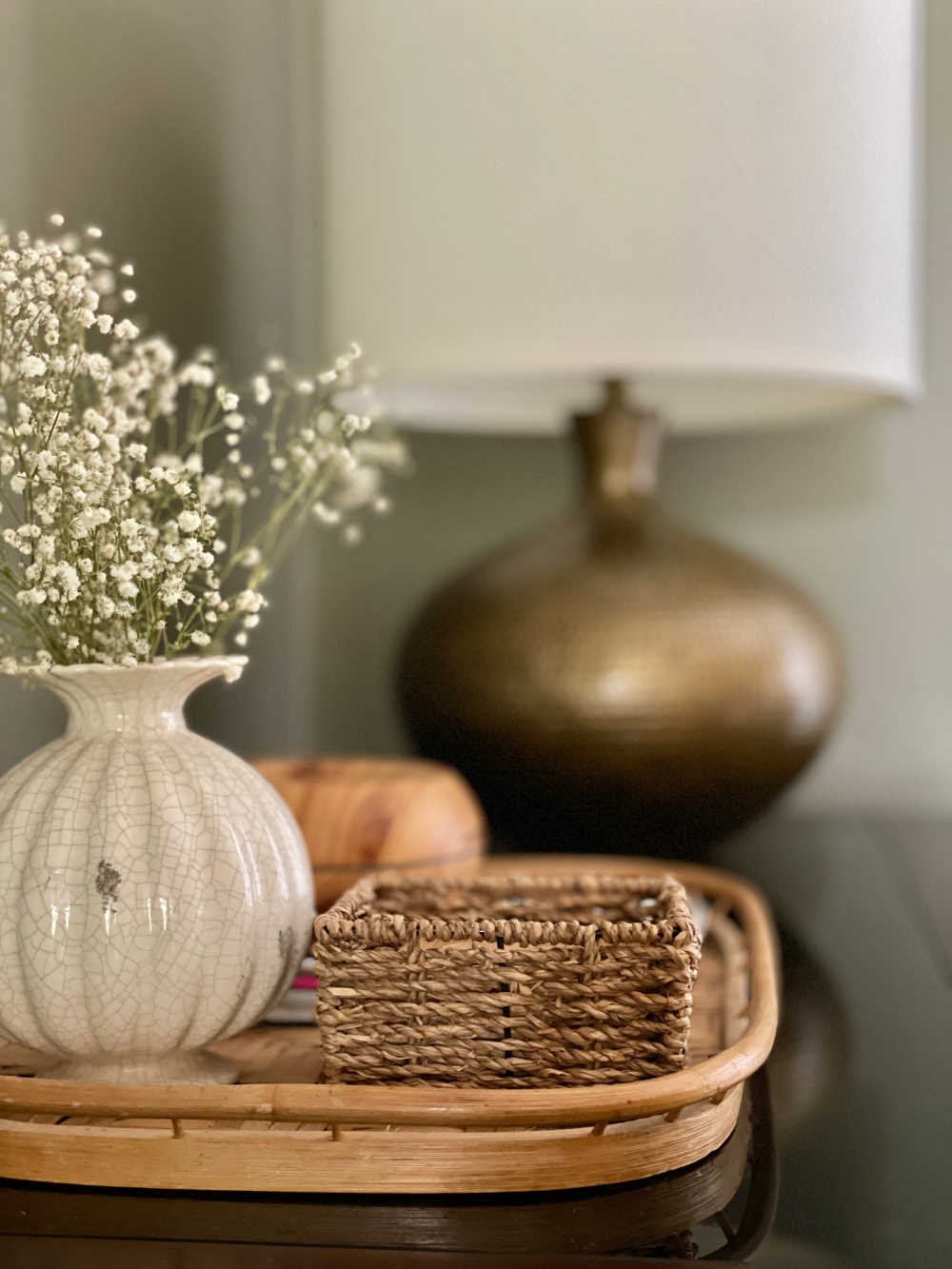 Desk with organized vintage rattan tray and vase of babys breath