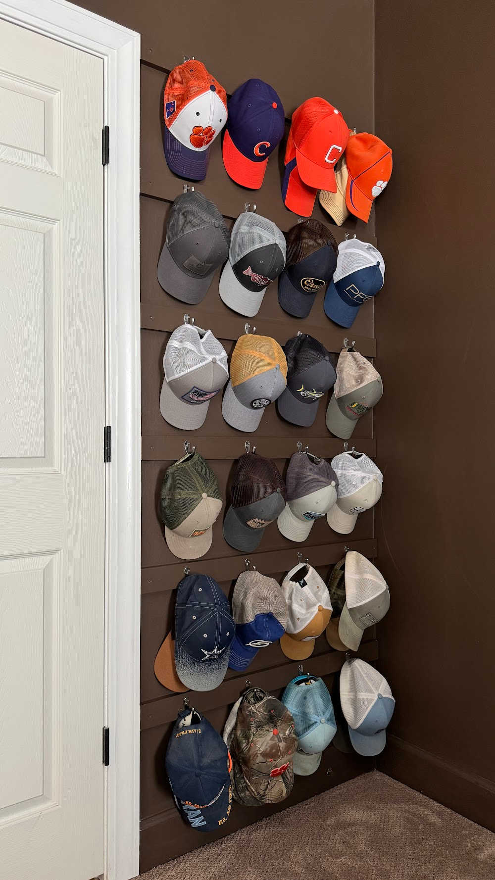 24 hats hanging on hooks built behind the door
