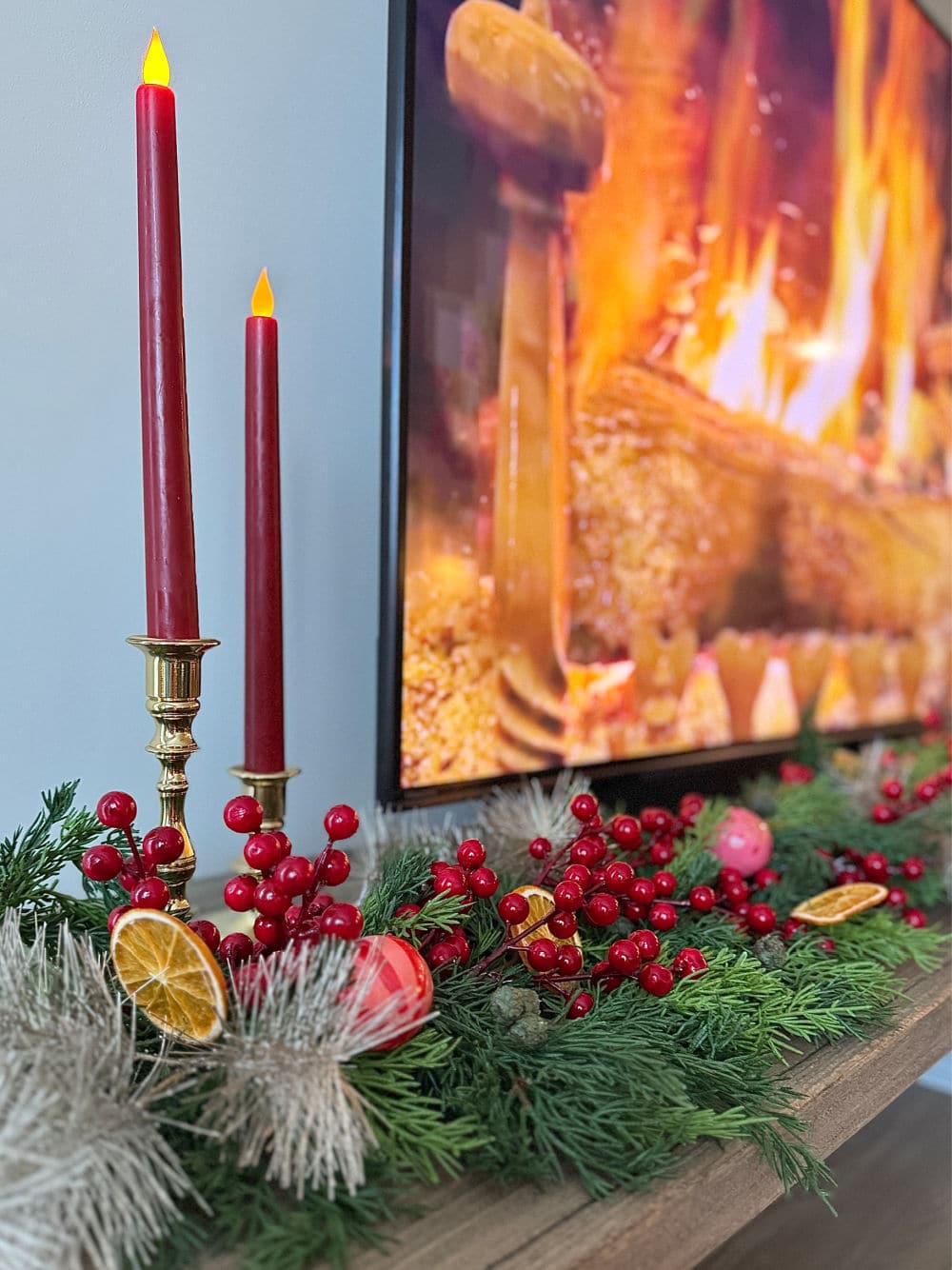 Apartment TV console decorated for Christmas with garland, berries and orange slices.